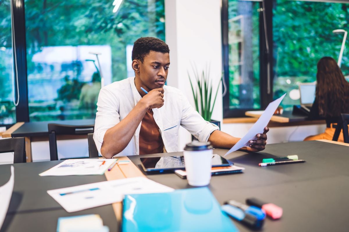 Un freelance assis sur son bureau lit un document