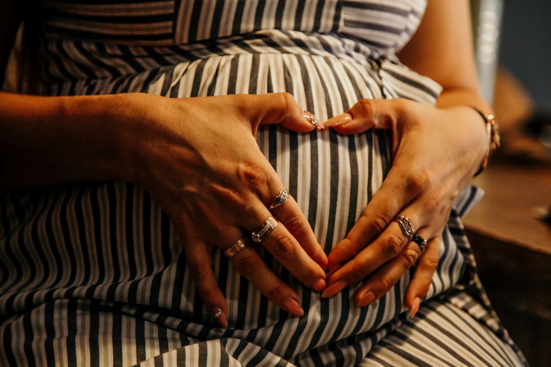 Une femme enceinte tient son ventre 