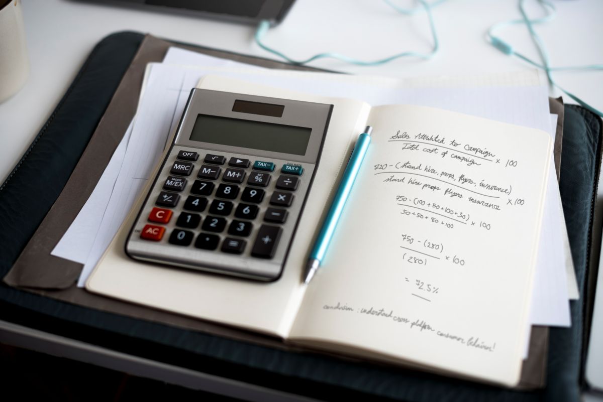 Une calculatrice, un carnet et un stylo sur un bureau