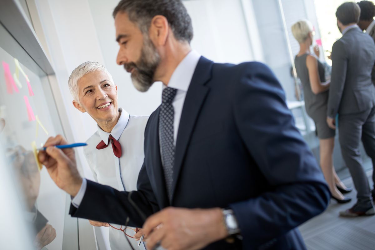 Un homme quarantenaire écrit sur un tableau.