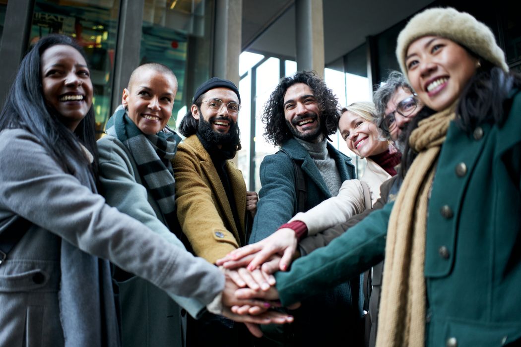 Groupe de gens d'affaires en plein air joignant les mains célébrant leur succès au travail.