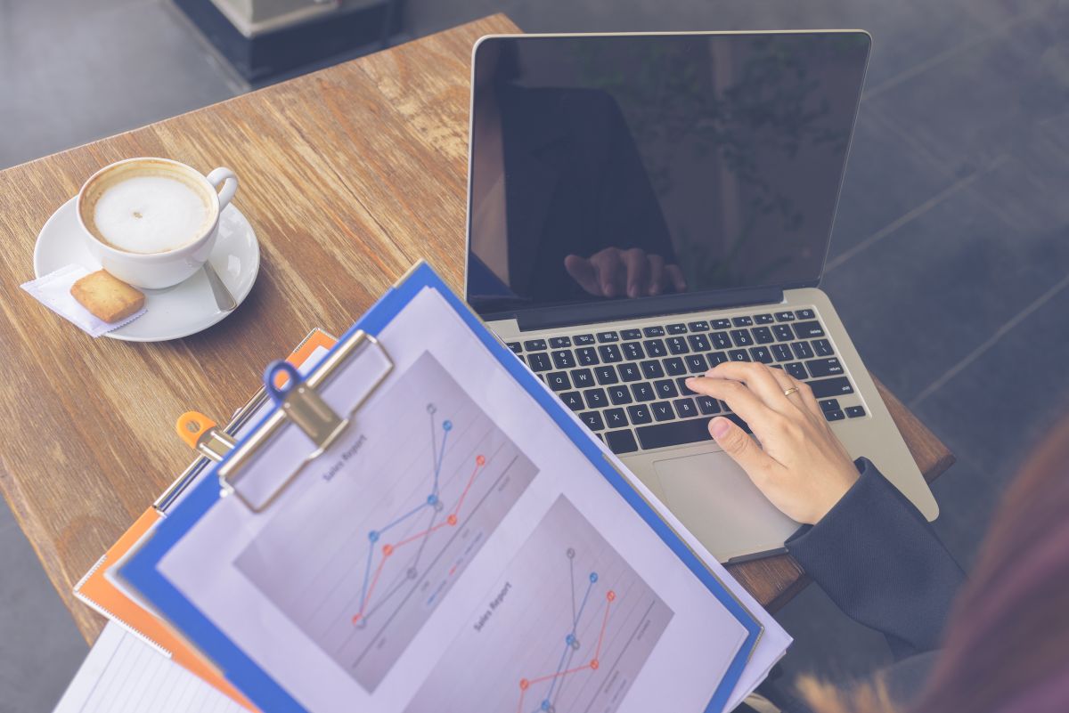 Un freelance regarde un document contenant un graphique et son ordinateur