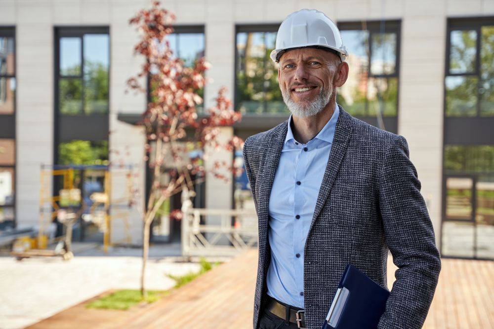 Un architecte souriant devant un bâtiment