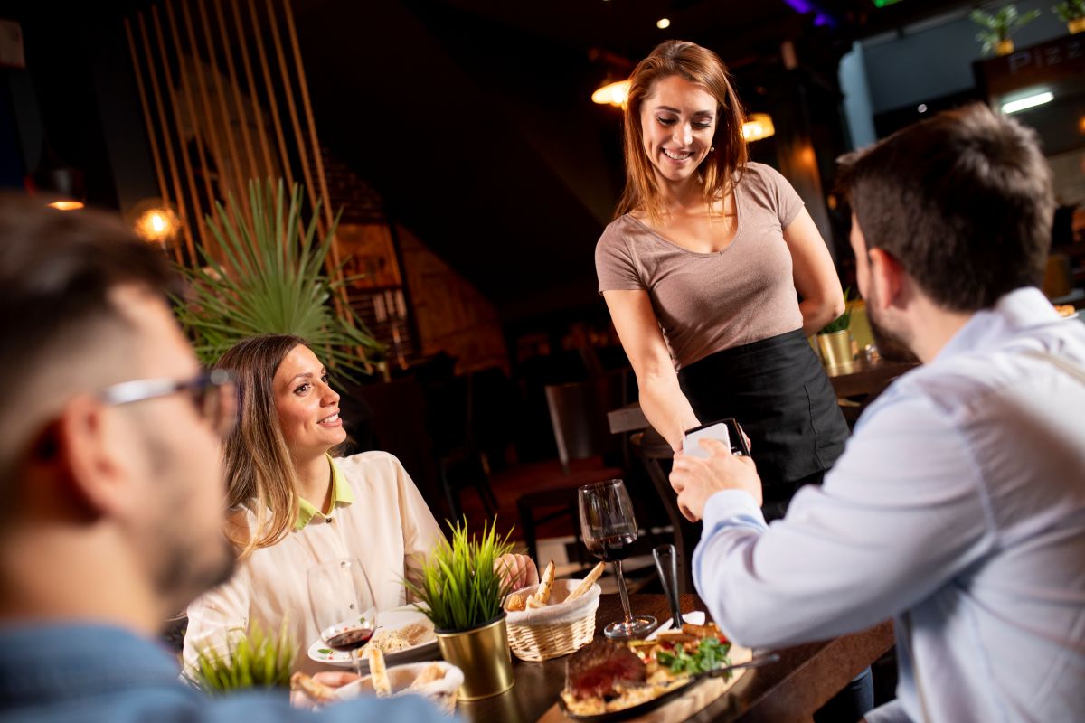 Jeune homme payant sans contact avec téléphone portable dans le restaurant 