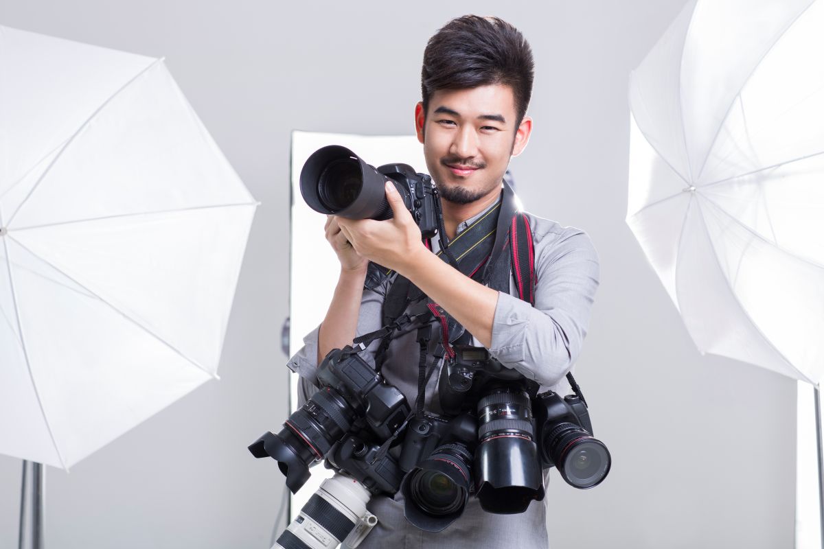 Photographe prenant une photo avec de nombreux appareils photo accrochés à son cou<br>
