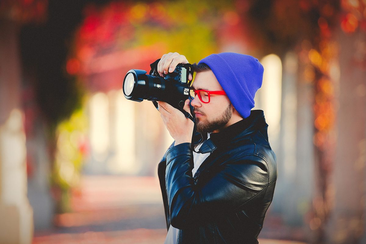 Un homme utilisant un appareil photo pour une photographie dans un parc
