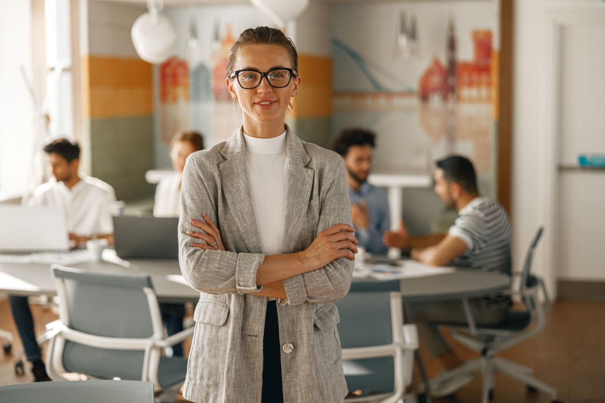 Une entrepreneuse souriante en costume debout dans un bureau moderne 